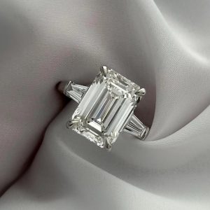 Emerald cut three-stone engagement ring with tapered baguette sides on polished band