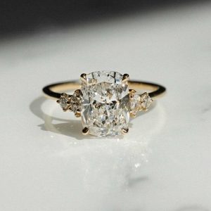 Cushion-cut three-stone diamond engagement ring with graduated side stones
