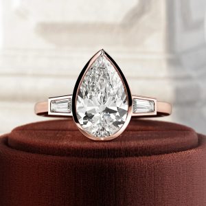 Pear cut bezel set engagement ring with baguette side stones and tapered shank
