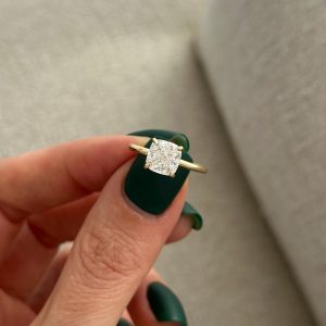 Cushion hidden halo engagement ring with four prongs and plain yellow band