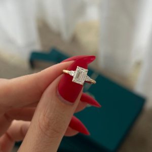 Emerald-cut three-stone engagement ring with plain polished band