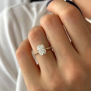 Oval diamond engagement ring with pavé band and four-prong compass setting