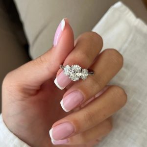 Elegant oval three-stone engagement ring with prong-set center and side stones