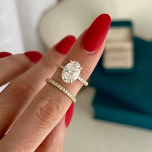 Oval halo pavé engagement ring with matching pavé diamond band, side by side