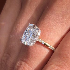 Cushion cut hidden halo engagement ring with pavé yellow band and split prongs