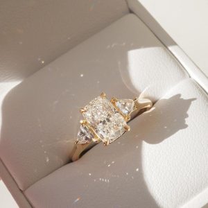 Radiant cut three stone diamond engagement ring with trillion sides on a plain band