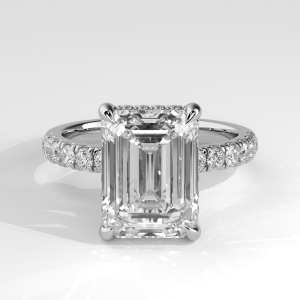 Emerald cut engagement ring with hidden halo and pavé band viewed at an angle